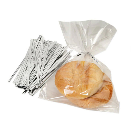 Silver metallic twist ties beside a clear cellophane treat bag tied at the top, holding two round cookies on a white background.