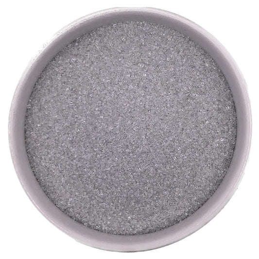 Top-down view of a white bowl filled with silver fine sanding sugar, showing tiny clear-to-silver crystals with a cool, metallic-looking shimmer.