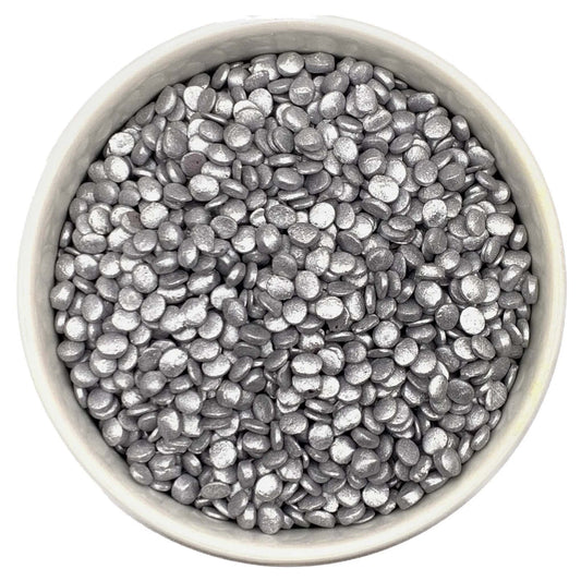 Metallic silver edible quins sprinkles in a white bowl, shown in a confetti shape, ideal for decorating cakes, cupcakes, cookies, and party desserts
