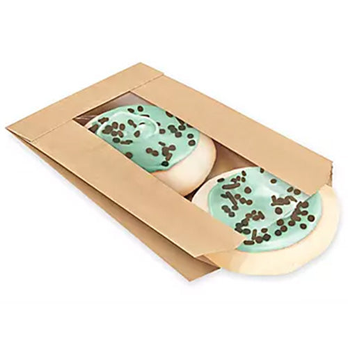Kraft paper cookie bag with a clear window showing two round iced cookies inside, each topped with teal icing and scattered chocolate sprinkles, on a white background.