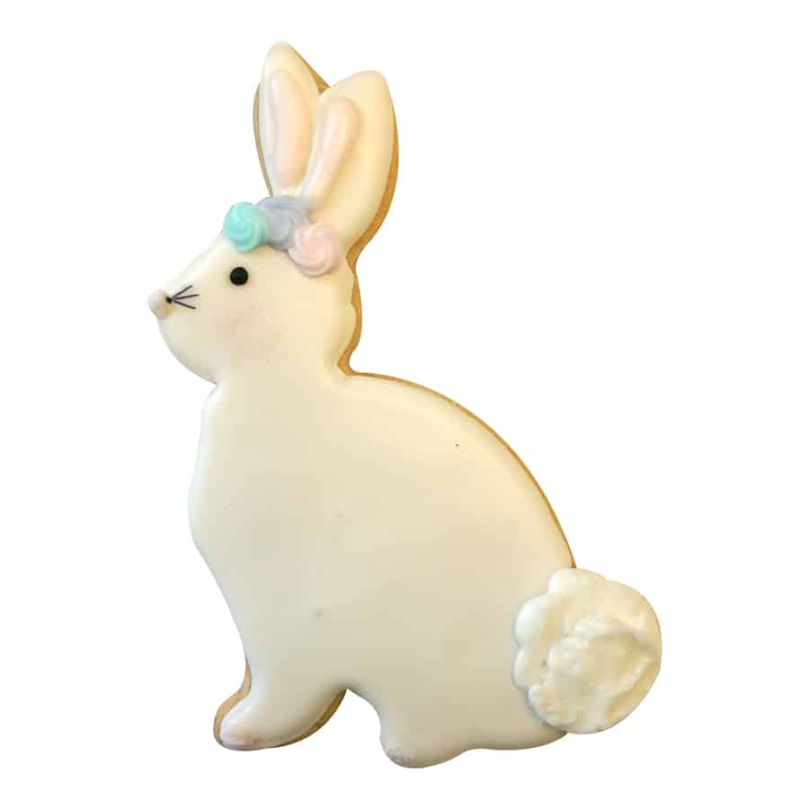 Decorated bunny-shaped cookie with white icing, pastel flowers, and a fluffy tail, made using the Sitting Bunny Cookie Cutter.