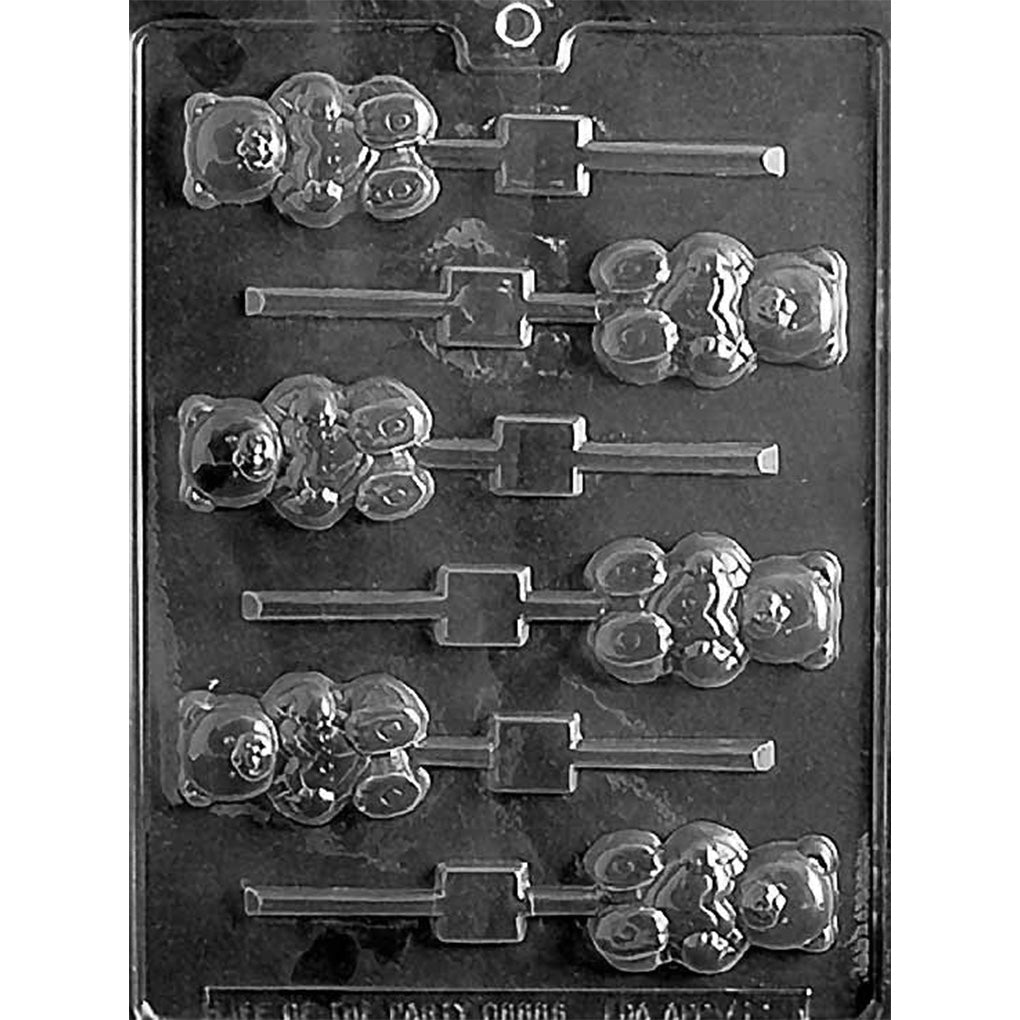 Clear plastic chocolate lollipop mold with six small teddy bear cavities holding hearts, arranged in two columns with stick channels, on a dark background.