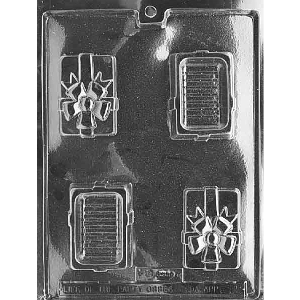 Clear plastic chocolate mold photographed on a black background, featuring cavities for a small rectangular gift box with a bow on top and matching bottom pieces.