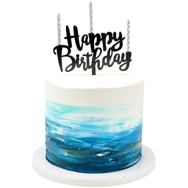 White and blue watercolor-style frosted cake topped with three silver spiral candles and a black “Happy Birthday” topper.