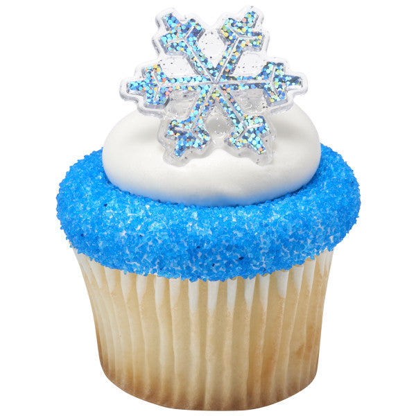 Vanilla cupcake with white frosting and blue sugar crystals topped with a hologram snowflake ring for a winter-themed decoration.