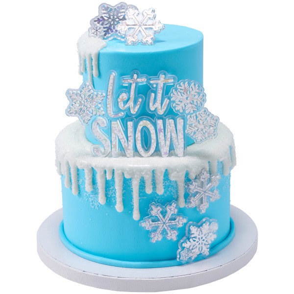 Two-tiered blue cake decorated with hologram snowflake rings and a 'Let It Snow' cake topper, perfect for winter celebrations.