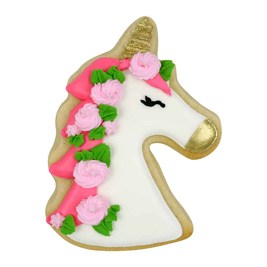 Decorated unicorn cookie with white icing, pink floral mane, green leaves, and gold accents on the horn and snout.