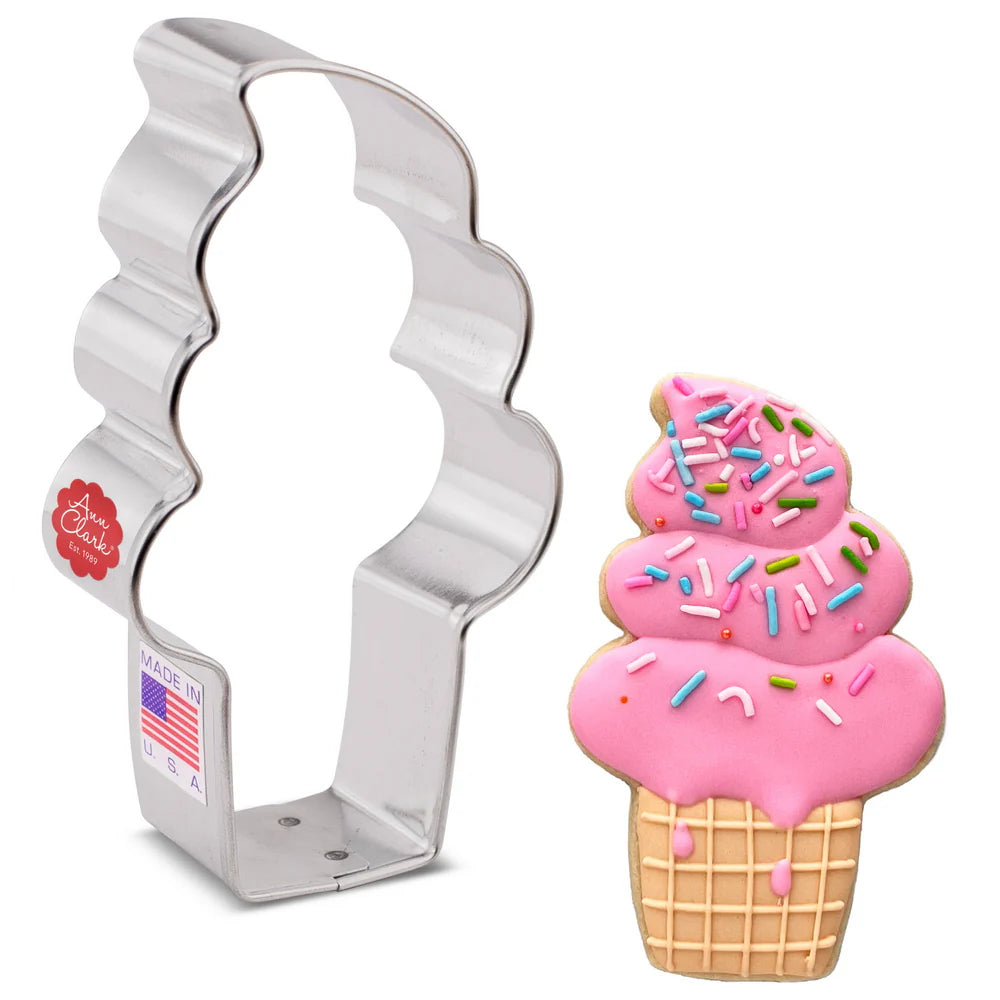 Ice cream cone cookie cutter next to a decorated cookie with pink icing, sprinkles, and a waffle cone design.