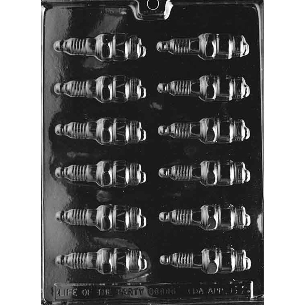 Clear plastic chocolate mold with multiple spark plug-shaped cavities arranged in rows, shown on a dark background with detailed ridges and automotive styling.