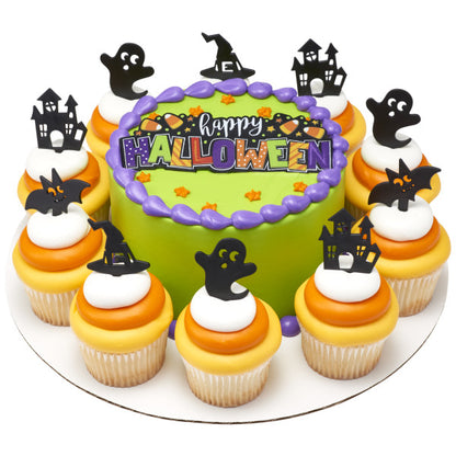Round green Halloween cake with coordinating cupcakes topped with ghost, haunted house, bat, and witch hat picks arranged around the edge.