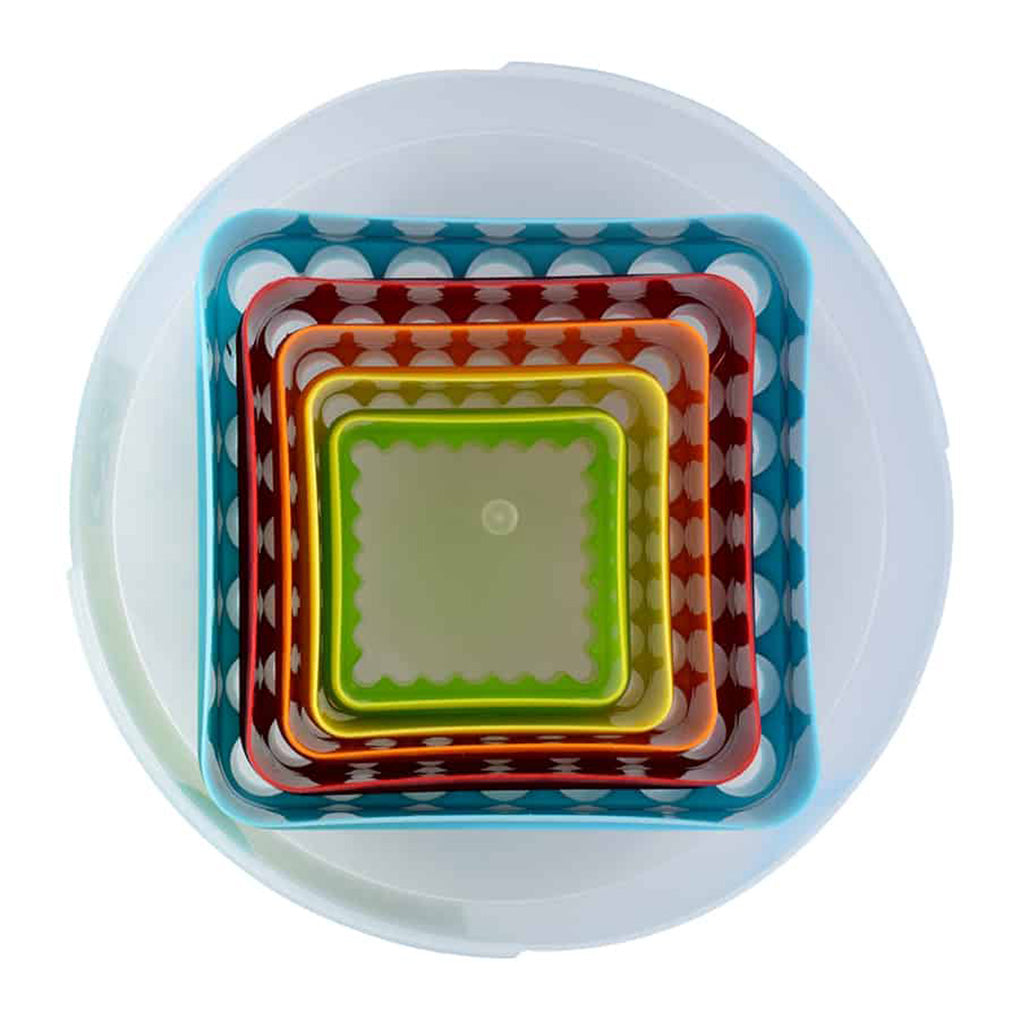 Top-down view of nested square cookie cutters inside a clear round container, showing the layered colors and fluted scallop edges.