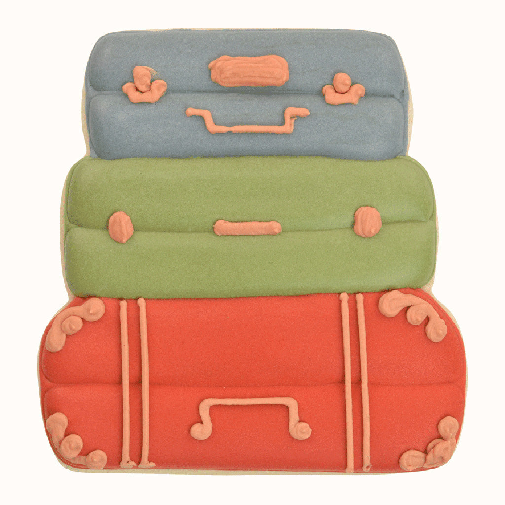 Decorated cookie shaped like a stack of vintage suitcases, featuring intricate icing details in blue, green, and red.