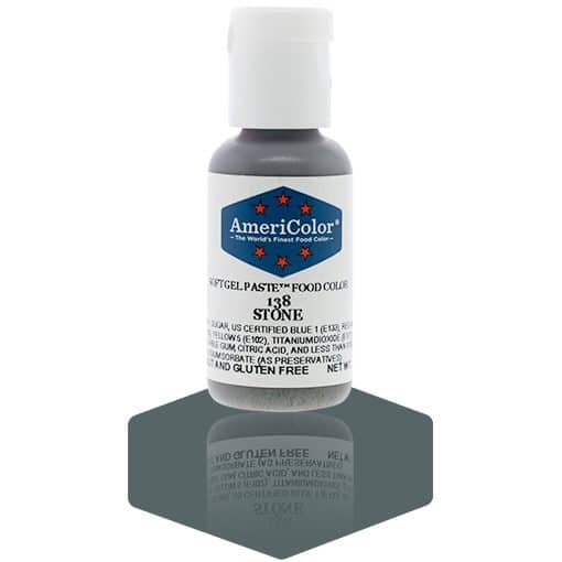 A bottle of AmeriColor Stone soft gel paste food coloring with a white cap, blue label, and red stars, positioned on a dark stone gray reflective surface with the bottle’s reflection clearly visible.