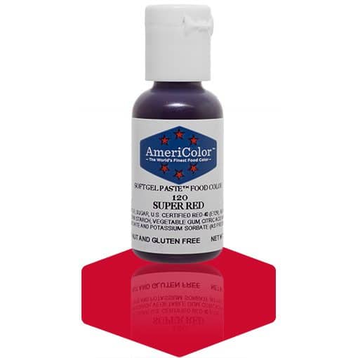 A bottle of AmeriColor Super Red soft gel paste food coloring with a white cap, blue label, and red stars, standing on a bright red reflective surface that mirrors the bottle.