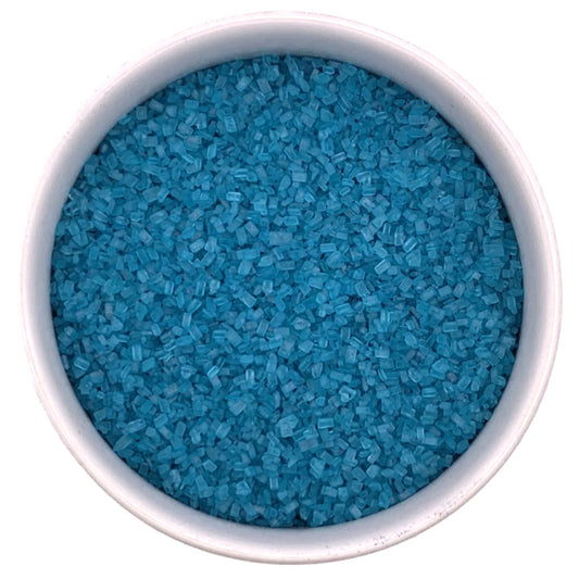 Top-down view of a white bowl filled with teal coarse sanding sugar crystals, showing chunky sparkling granules and rich blue-green color.