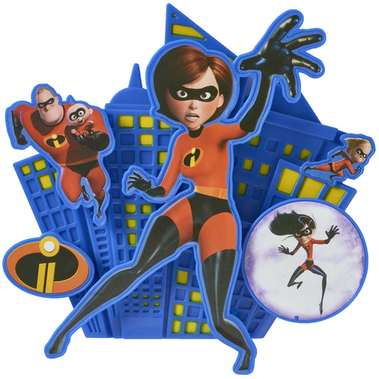 3D superhero-themed cake topper with a blue city skyline backdrop and a central masked character in a red suit reaching forward, with smaller character cutouts and an “i” logo.