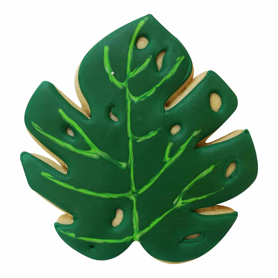 Decorated tropical leaf cookie with deep green icing and delicate vine details, perfect for island-themed baking.