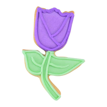 Decorated tulip cookie with purple icing on the bloom and green icing on the stem and leaves, designed with detailed piping work.