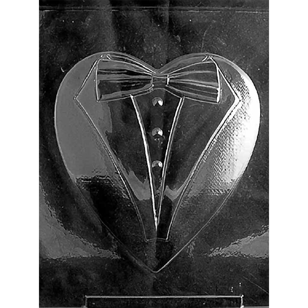 Clear plastic chocolate mold photographed against a black background featuring a large heart cavity decorated as a formal tuxedo with lapels, bow tie, shirtfront, and buttons.