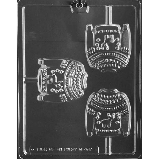 Clear plastic chocolate lollipop mold photographed on a dark background with three ugly Christmas sweater-shaped cavities, each showing knit-style pattern bands, a center animal motif, and a stick channel.