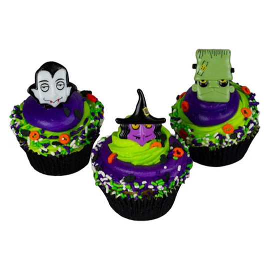 Three Halloween cupcakes topped with Monster Mix cupcake rings featuring a vampire, purple witch, and green stitched monster over purple and green frosting.