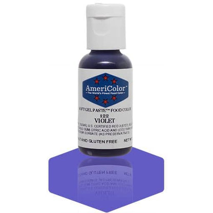 A bottle of AmeriColor Violet soft gel paste food coloring with a white cap, blue label, and red stars, placed on a purple reflective surface with the bottle’s reflection clearly visible.