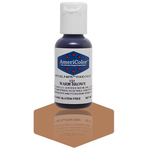 A bottle of AmeriColor Warm Brown soft gel paste food coloring with a white cap and blue label featuring red stars, standing on a glossy brown reflective surface that mirrors the bottle.