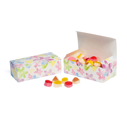 Watercolor floral candy boxes, one open and filled with assorted pastel candies, with a few candies in front.