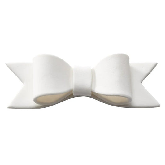 White gum paste bow tie cake decoration with sculpted loops, a raised center knot, and pointed ribbon tails shown against a white background.