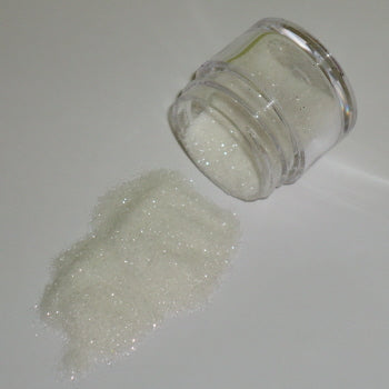 Fine white Galaxy Glitter Dust spilled from a jar, giving off a soft, snowy sparkle with gentle rainbow reflections.
