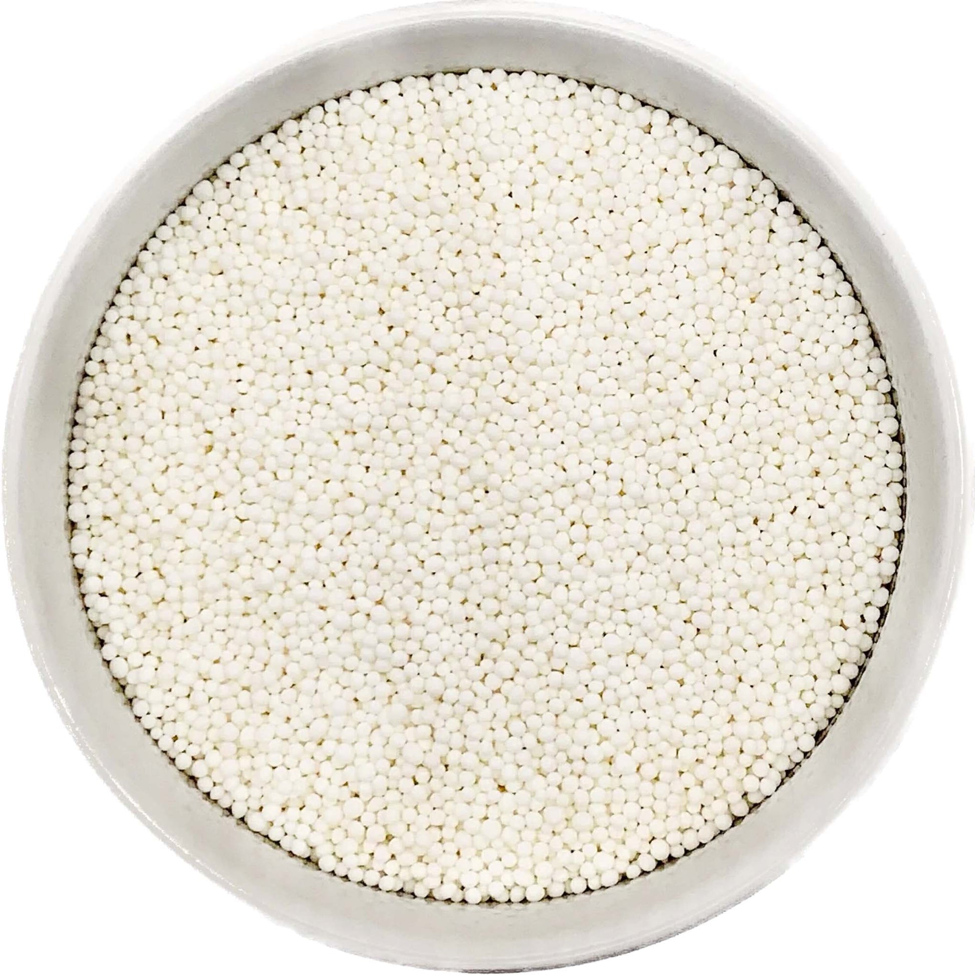Bowl of bright white nonpareil sprinkles on a white background.