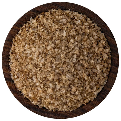 Overhead view of applewood smoked sea salt in a round dark wooden bowl, showing tan-brown flake crystals with uneven, rustic texture.