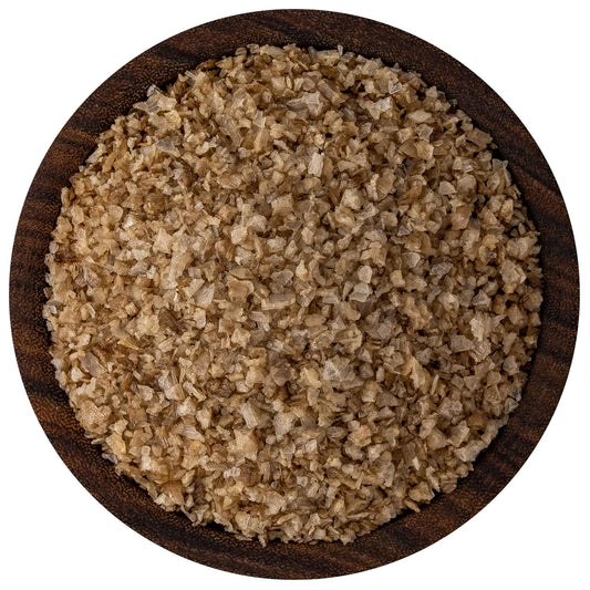 Overhead view of applewood smoked sea salt in a round dark wooden bowl, showing tan-brown flake crystals with uneven, rustic texture.