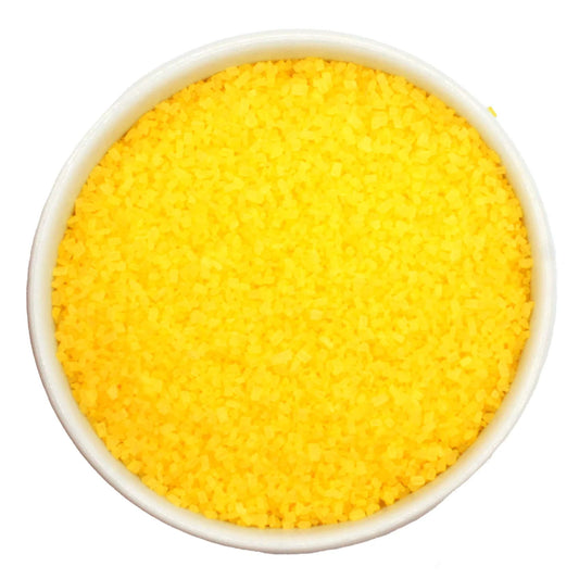 Top-down view of a white bowl filled with yellow coarse sanding sugar crystals, showing bright yellow, chunky granules packed closely together.