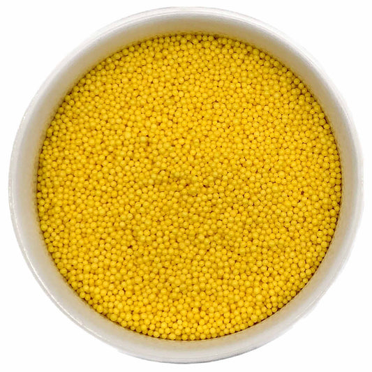 Bowl filled with bright yellow nonpareil sprinkles on a white background.