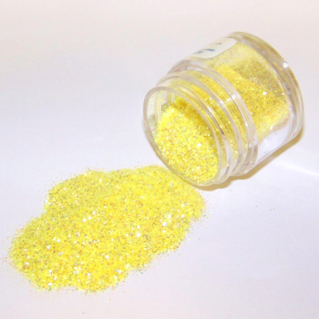 Open jar of Yellow Rainbow Galaxy Glitter Dust tipped on its side with sparkling yellow glitter dust spilled onto a white surface.