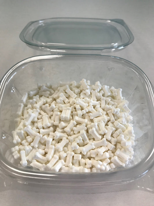 Close-up of a plastic container filled with white bone-shaped sprinkles, ideal for pet-themed or Halloween desserts.