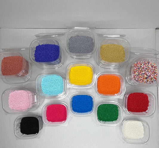 Assorted non-pareils sprinkles in multiple colors, displayed in small clear containers for decorating baked goods.