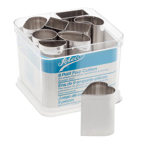 Stainless steel 9-piece petit four cutter set in assorted shapes, displayed in a clear storage container with one cutter in front.