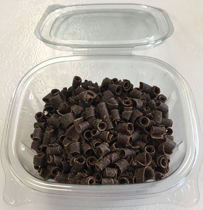 Clear plastic container of dark chocolate curls with lid open, ready for use as dessert toppings.