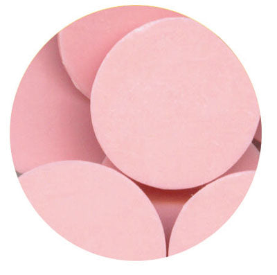 Close-up of light pink melting wafers with smooth, round discs stacked and overlapping inside a circular crop.