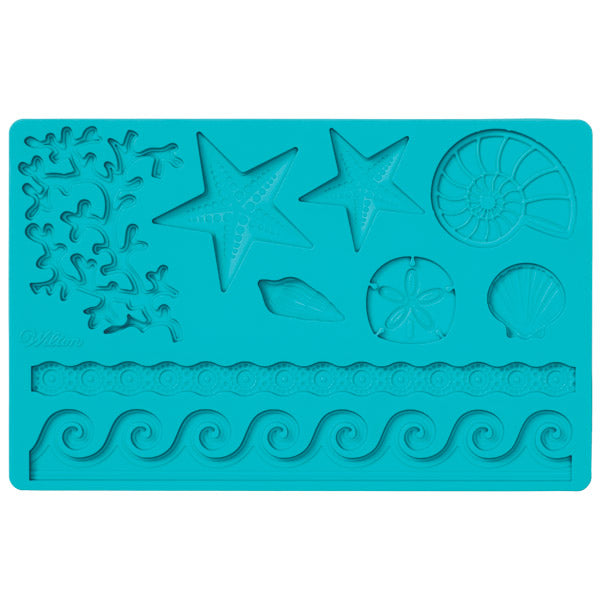 Wilton sea life fondant and gumpaste mold in teal blue, featuring molded designs of starfish, shells, coral textures, and wave borders on a rectangular silicone mat