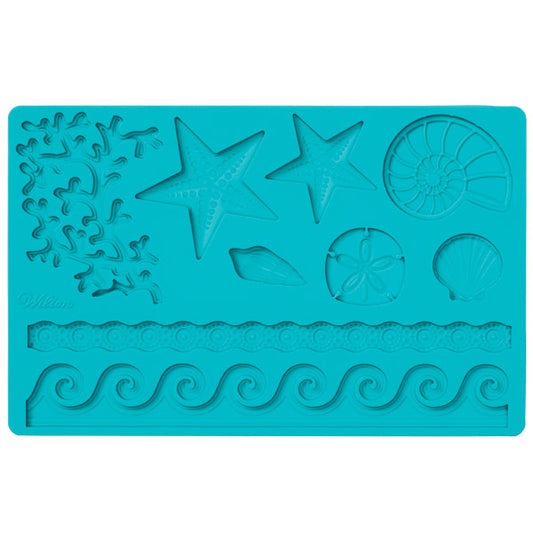 Wilton sea life fondant and gumpaste mold in teal blue, featuring molded designs of starfish, shells, coral textures, and wave borders on a rectangular silicone mat
